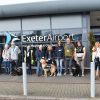 Staff, volunteers and puppies stand in front of the airport building.