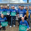 A group of men wearing blue Men's Walk t-shirts and holding up signs in support of Hospiscare