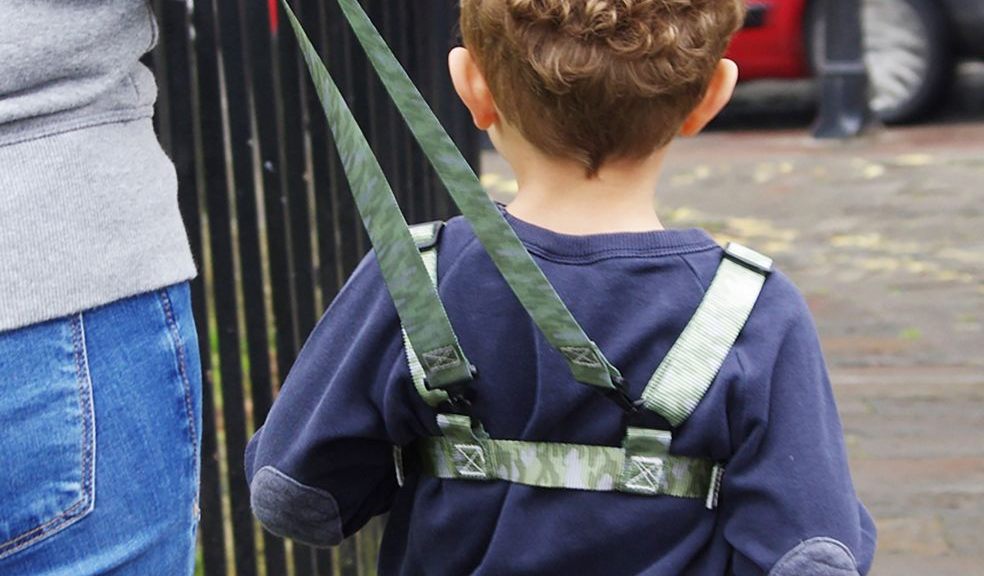 Toddler walking on pavement in camouflage baby reins 