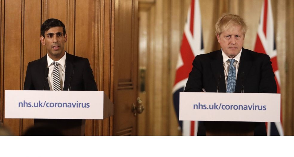 Boris Johnson looking unhappy at a press conference, accompanied by Rishi Sunak