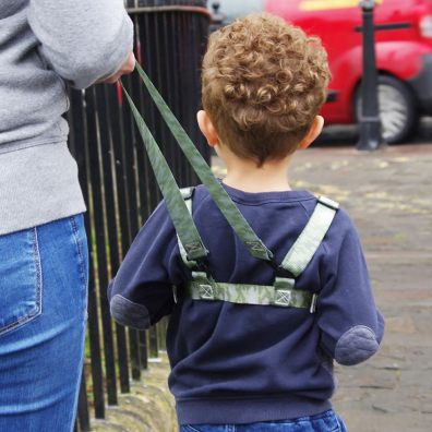 Toddler walking on pavement in camouflage baby reins 