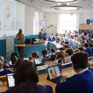 Children in uniform working with digital devices in the Year 6 lecture theatre